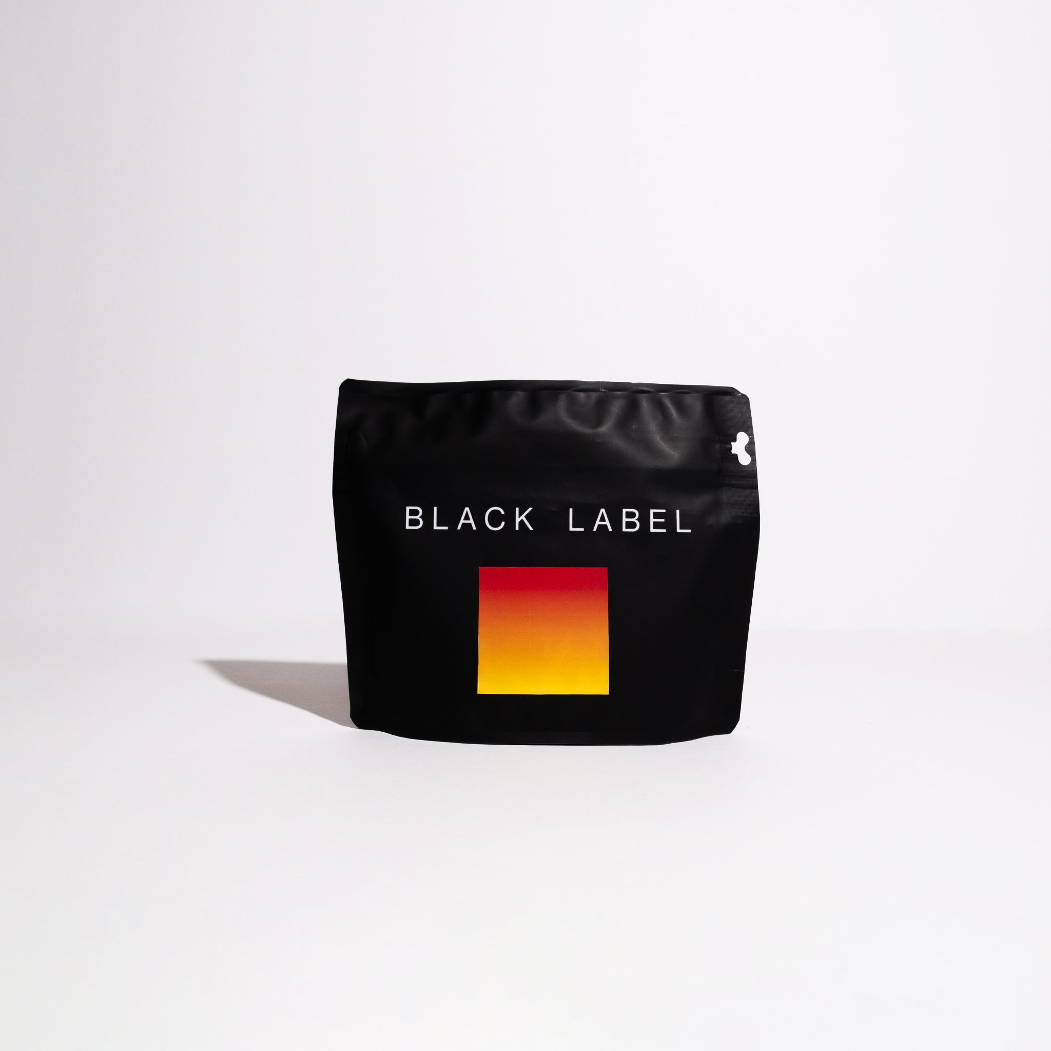 Matte-black stand-up pouch labeled “BLACK LABEL” with a red-to-yellow gradient graphic, featuring Arturo Paz - Jurassic DRD Gesha specialty coffee.