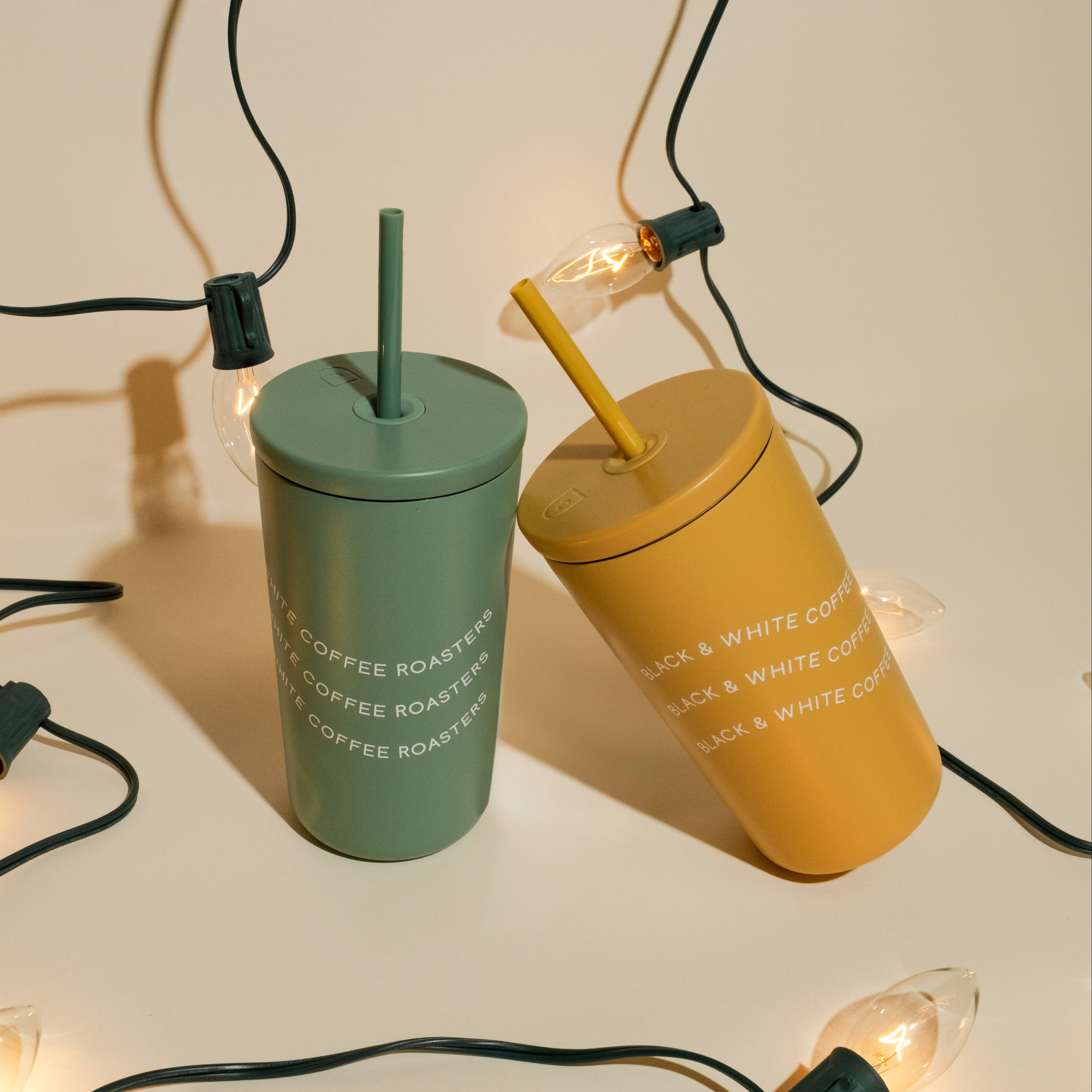 Two cold cups with black and white coffee roasters written across the cups on a holiday themed back drop.