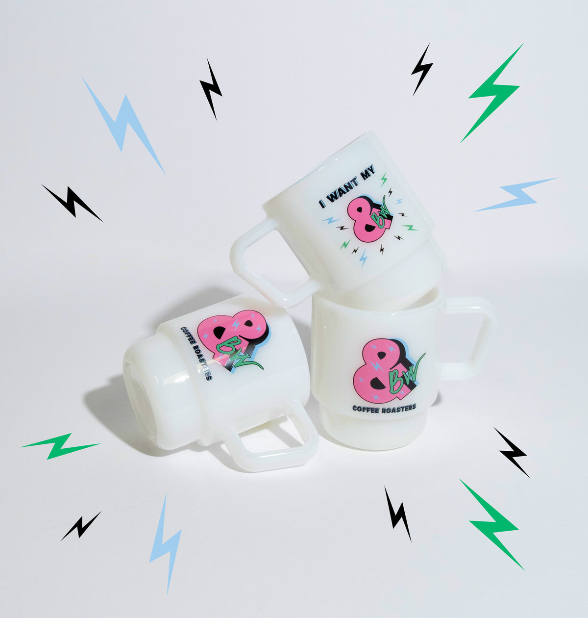Three white ceramic mugs stacked together on a white surface against a white background. Each mug features a pink & graphic with a green BW and small black text.