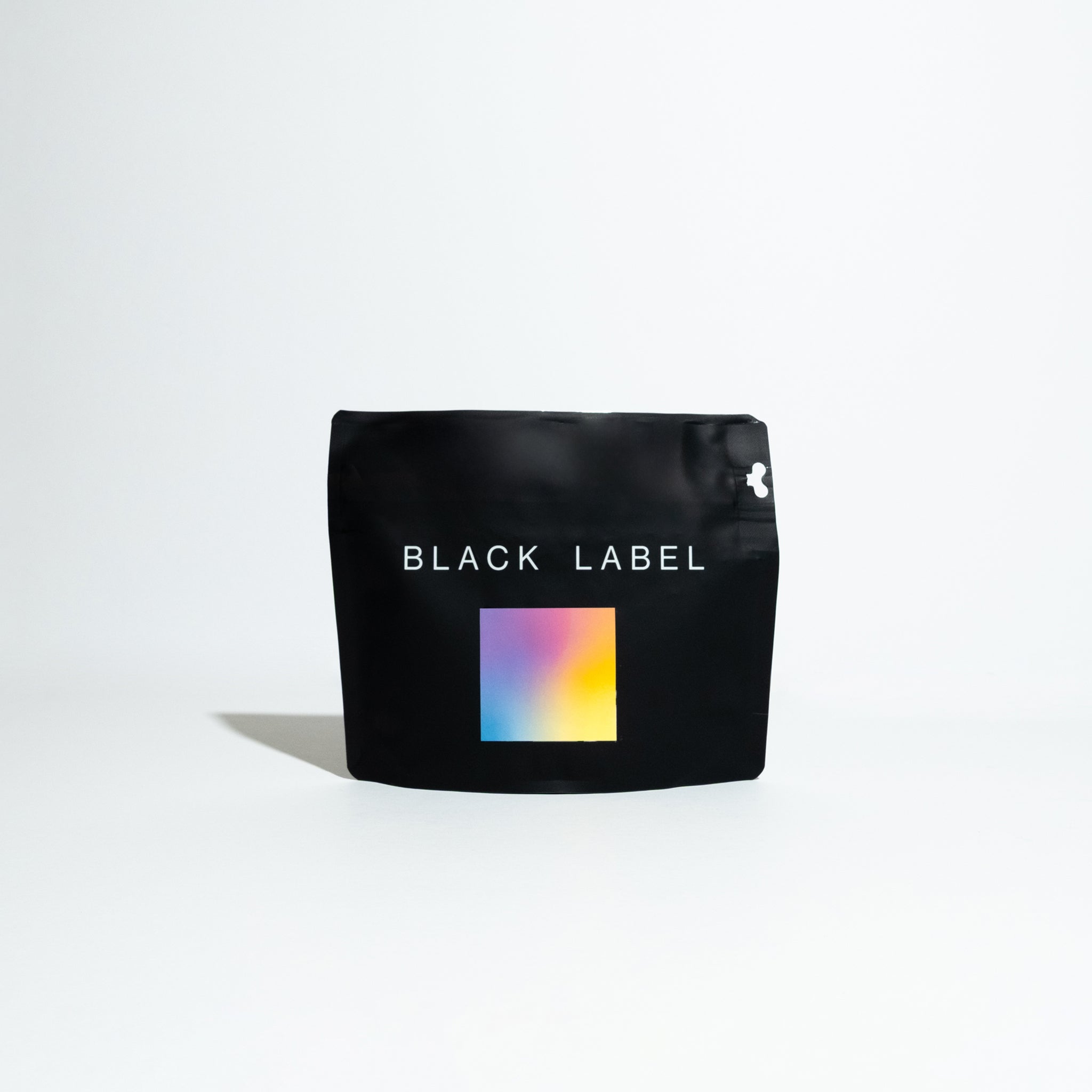 Black bag featuring a colorful square, representing the Jardines del Encanto - Maragesha coffee, a specialty product from Colombian producer Felipe Arcila.
