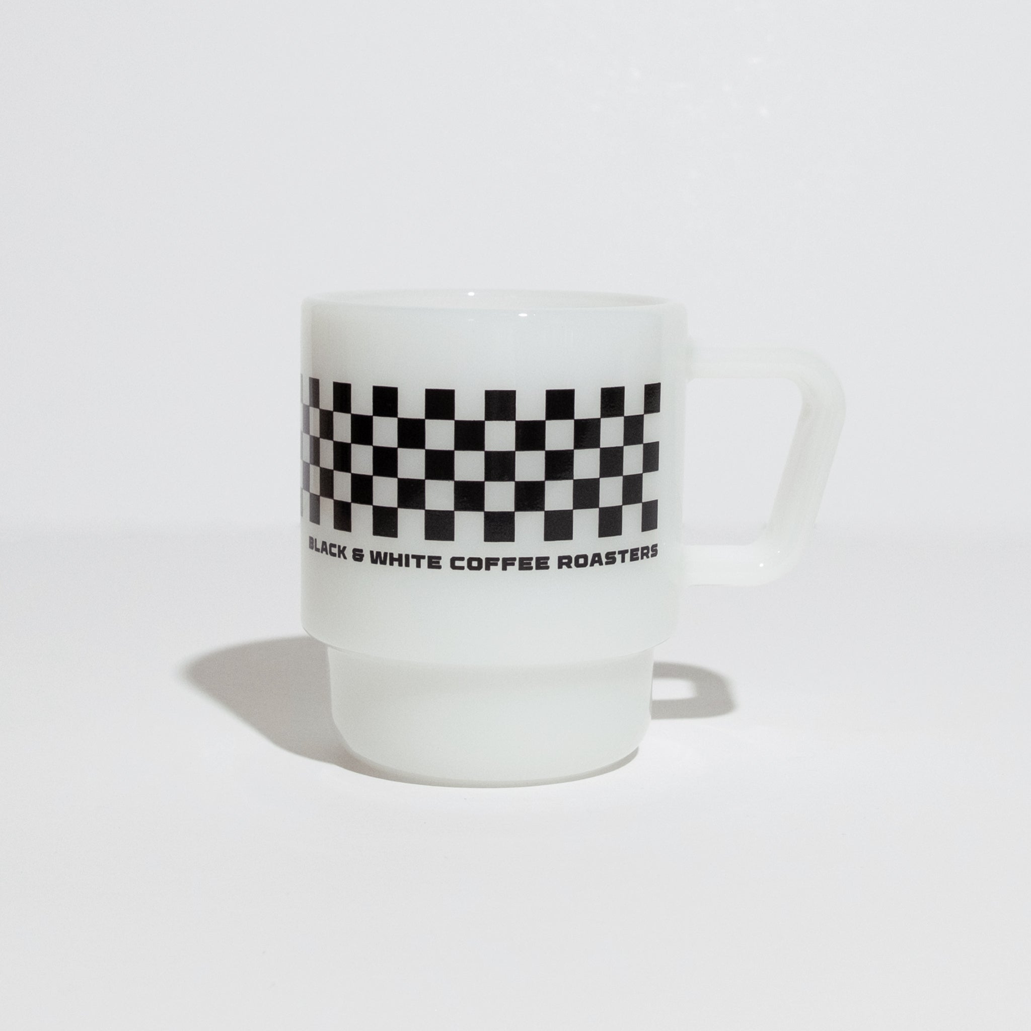 B&W Milk Glass Mug with a black checkerboard band and BLACK & WHITE COFFEE ROASTERS text, featuring a vintage look and durable design.