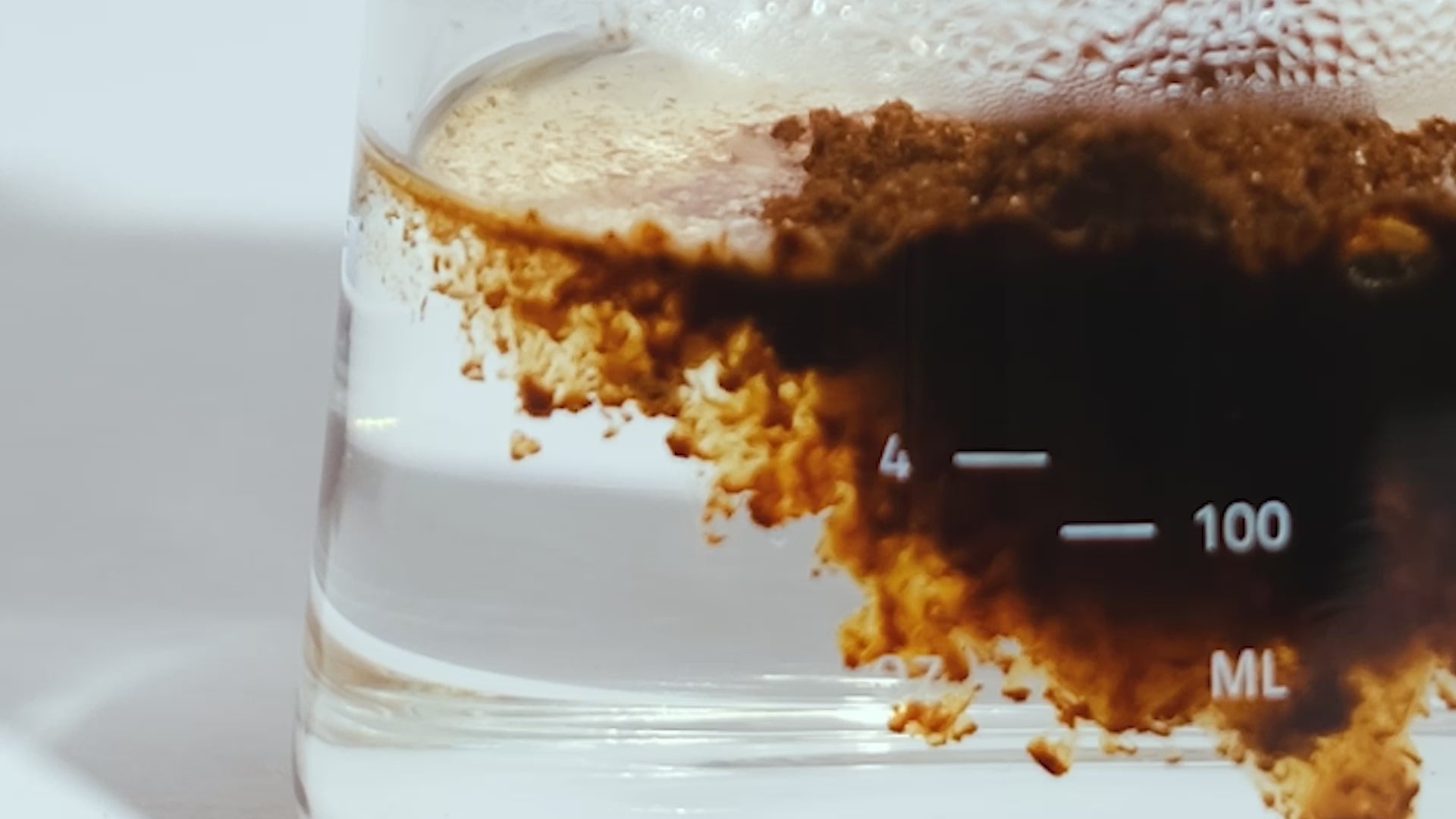 Instant Coffee being dissolved in a glass beaker in warm water.