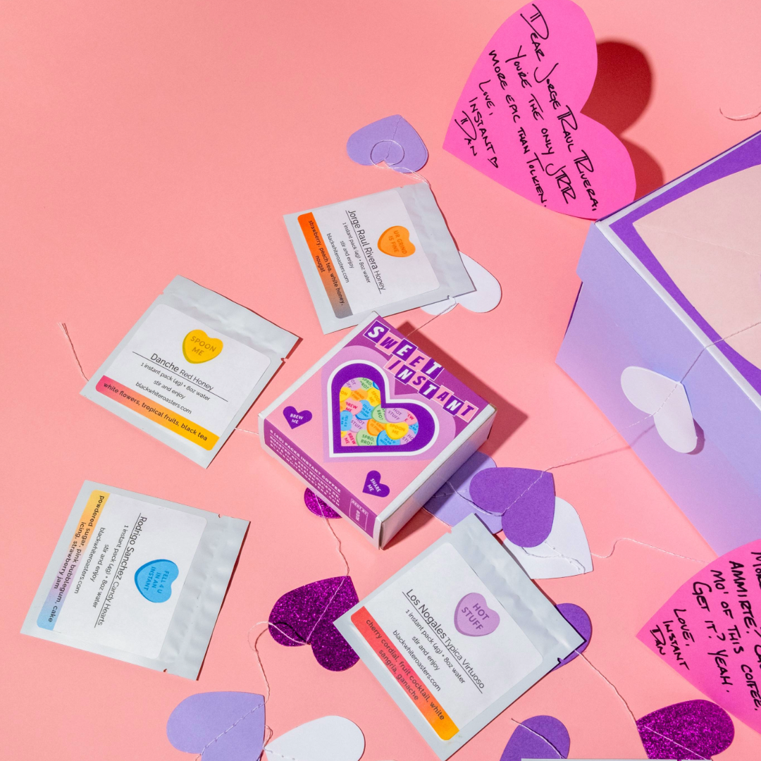 Valentine's Variety Pack - Instant Coffee with purple gift box, heart messages, and six single-serve packets showcasing specialty coffee origins and tasting notes.