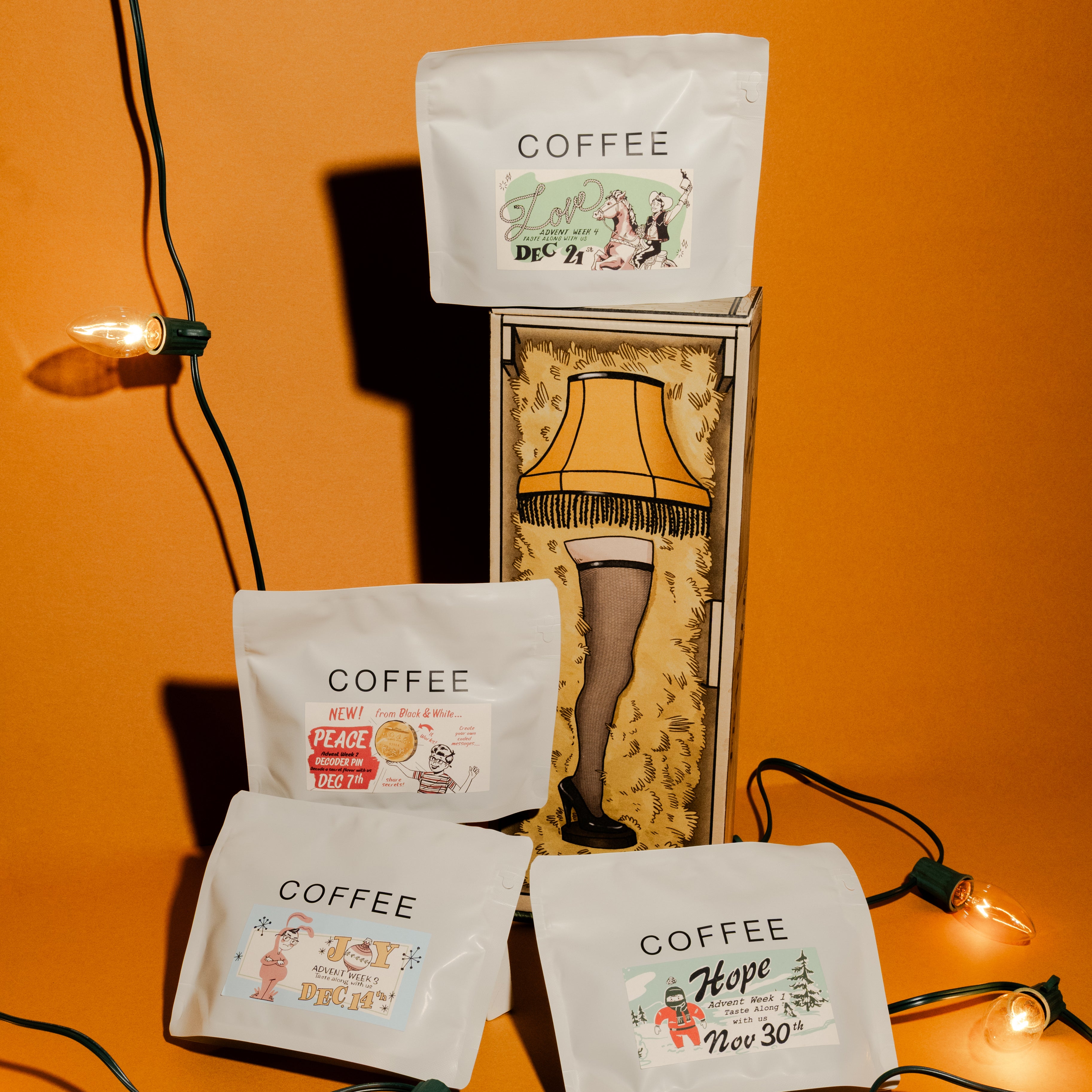 2025 B&W Advent Calendar features four holiday-themed coffee pouches with tags: Hope, Joy, Peace, Love, arranged around a decorative “leg lamp” box.