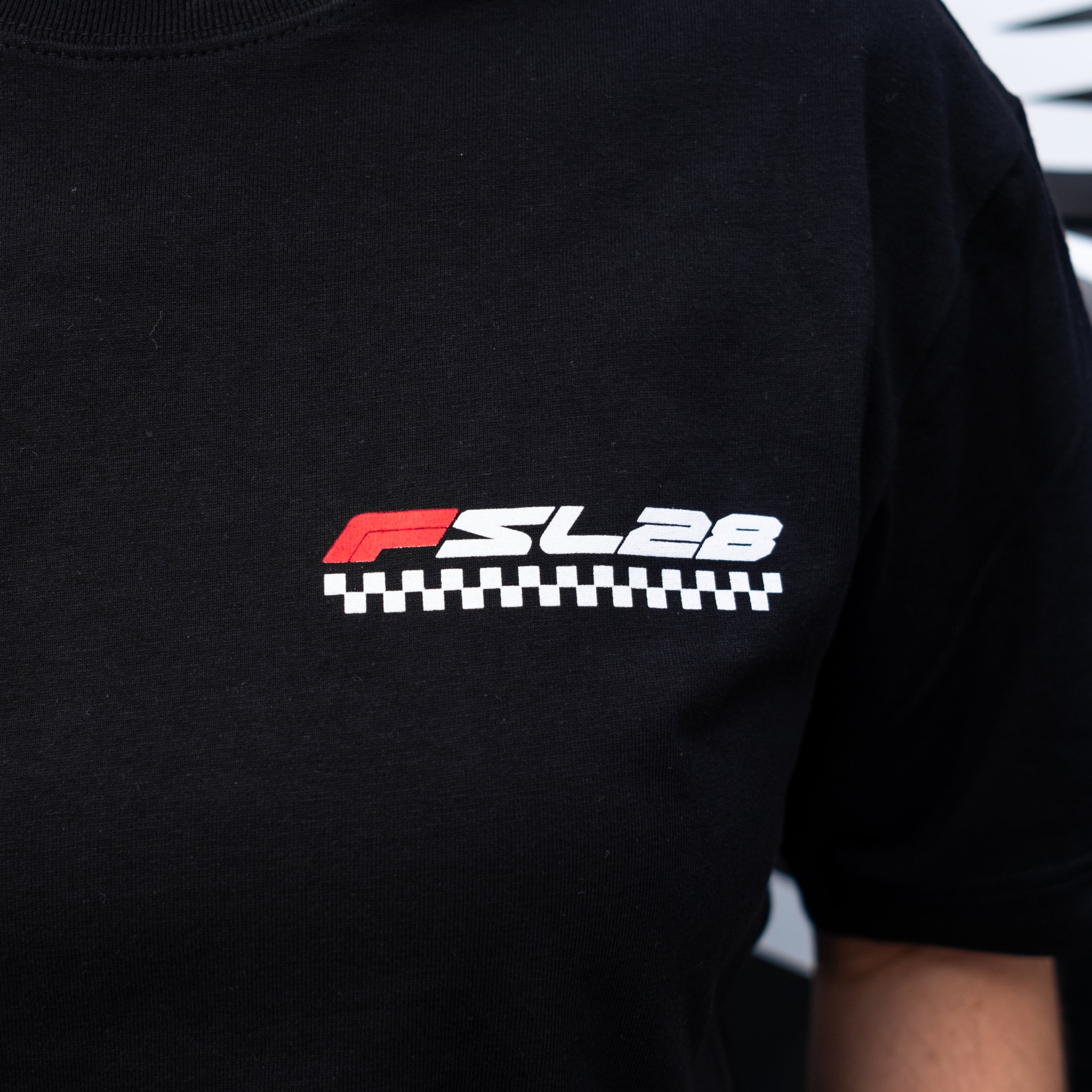 Black FSL28 Birthday Shirt featuring a small FS Lab 28 logo with a checkered-flag stripe on the chest, inspired by cutting-edge coffee exploration.