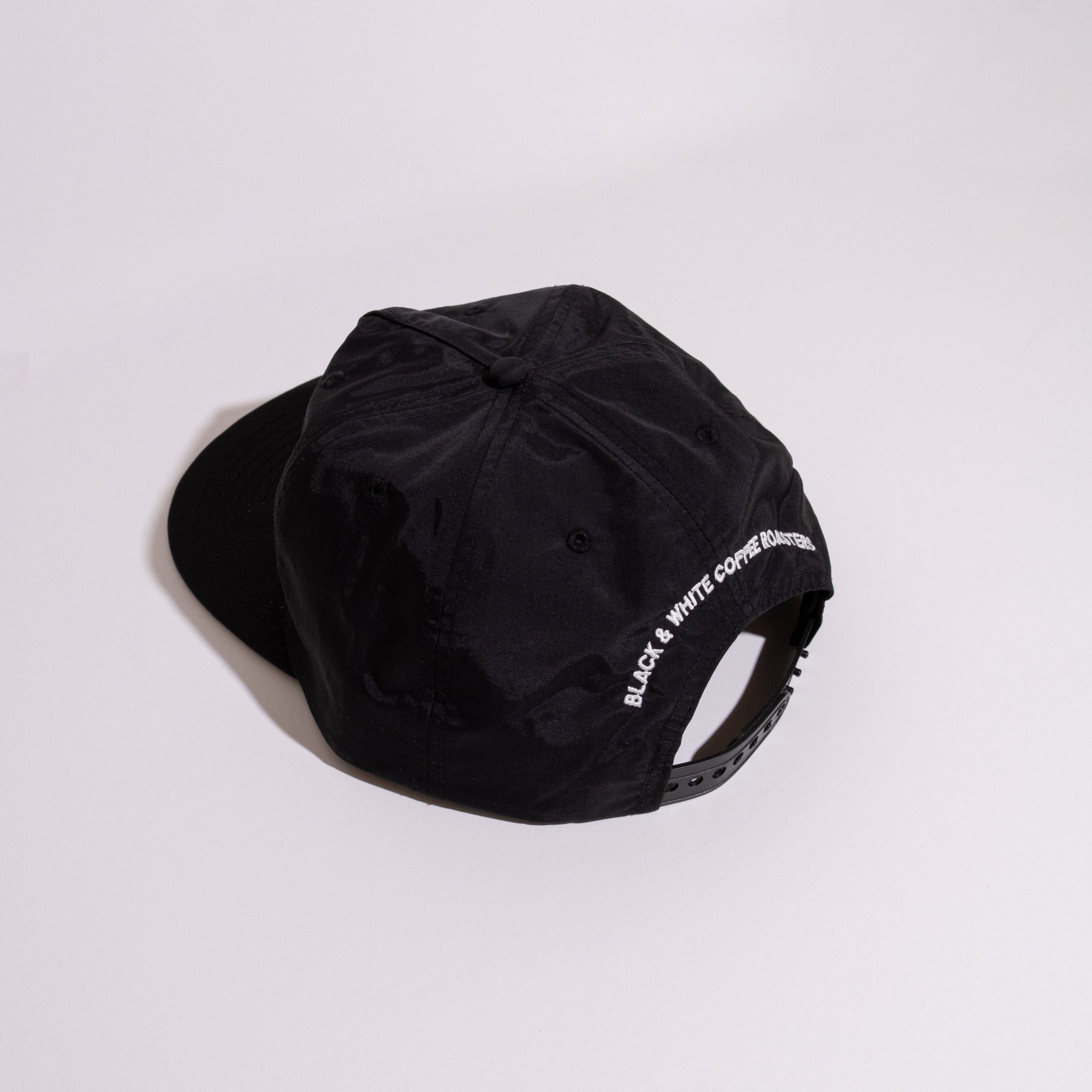 FSL28 Racing Team Hat featuring a six-panel design with “BLACK & WHITE COFFEE ROASTERS” embroidered, snap-back closure, and unique flip-up buckram style.