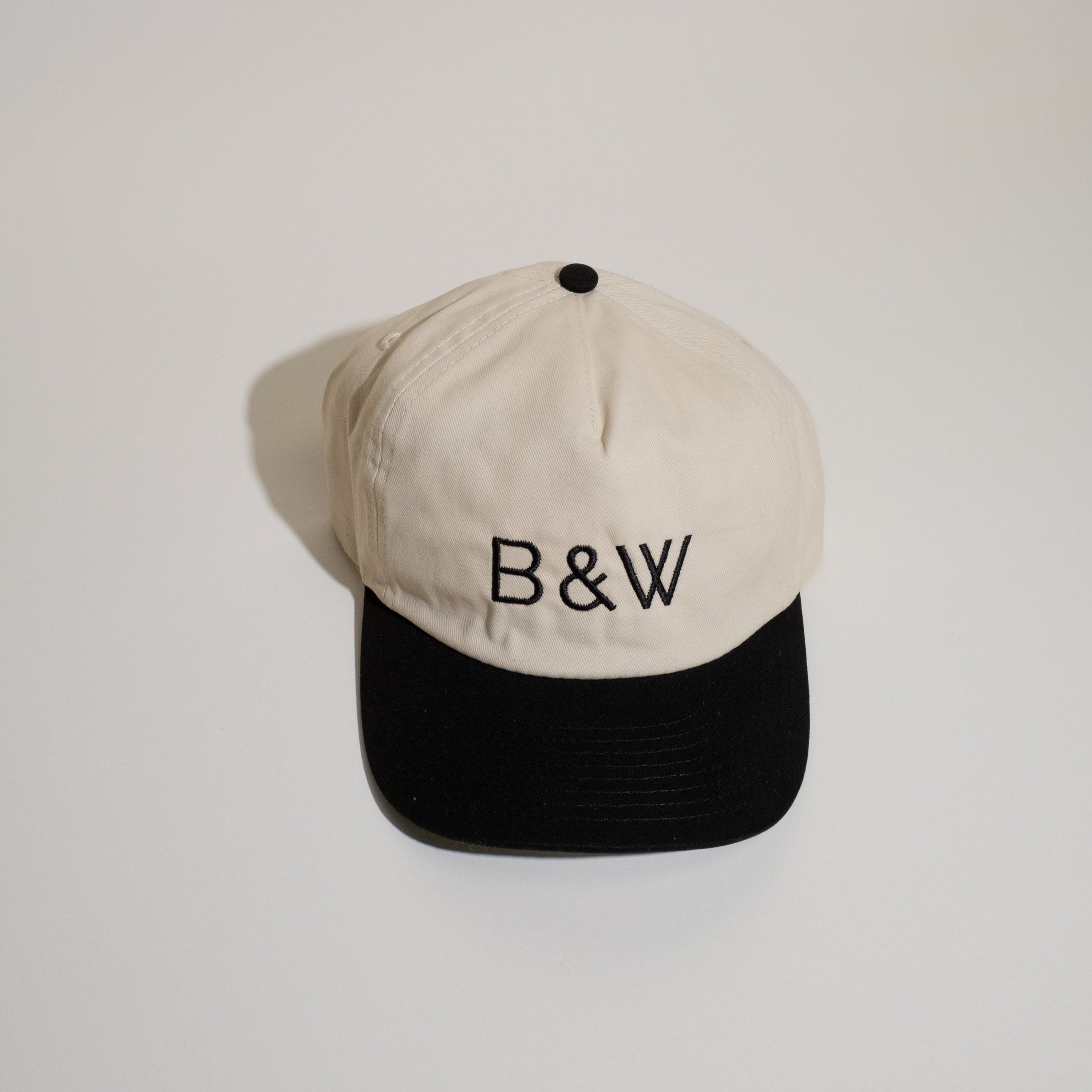 B&W Two Tone Hat with cream crown, black bill, B&W embroidery front, Black & White Coffee Roasters back, adjustable snapback, and pre-curved visor.