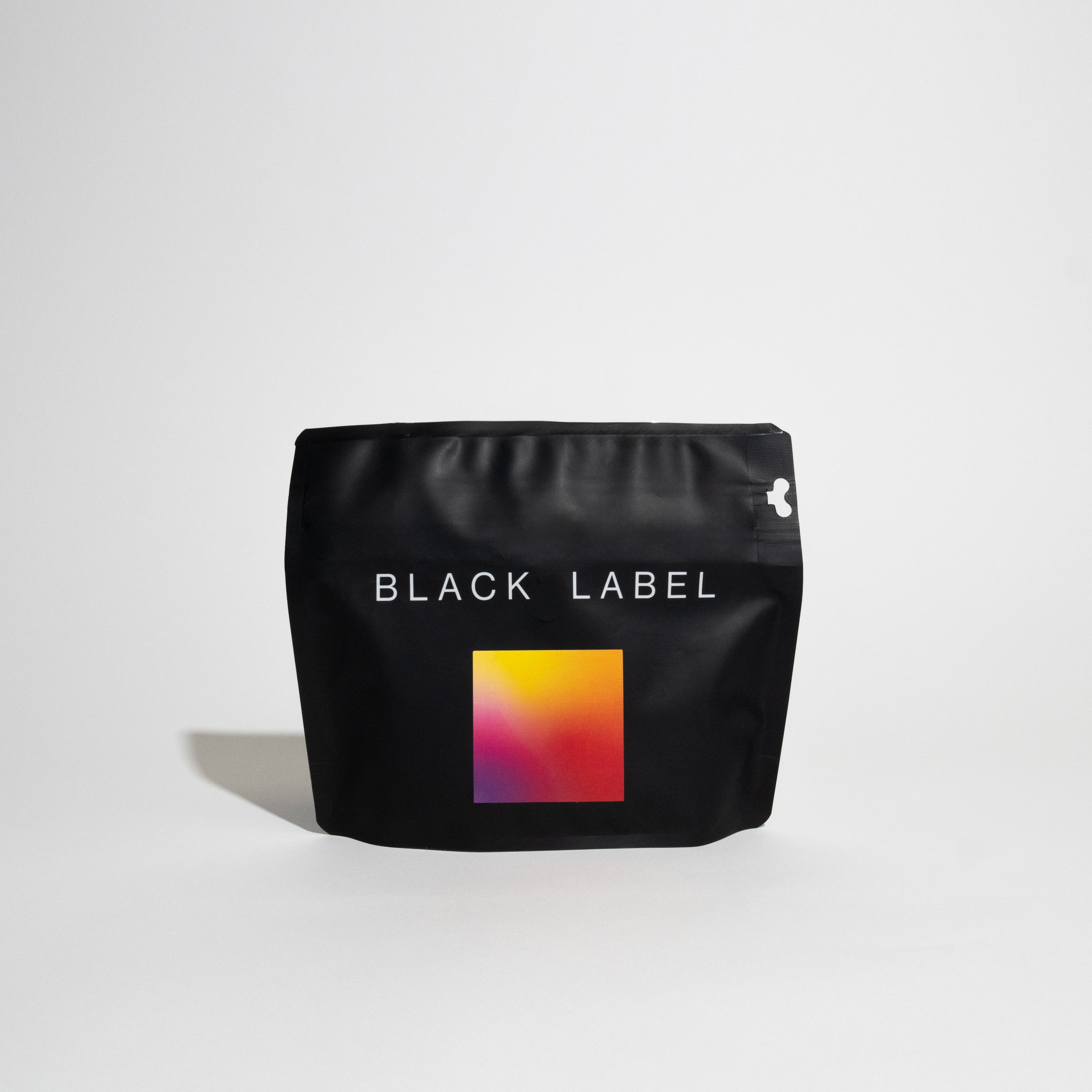 Matte-black pouch labeled BLACK LABEL, featuring a gradient square, containing Benjamin Paz - DRD Natural Gesha, a specialty coffee with unique processing.