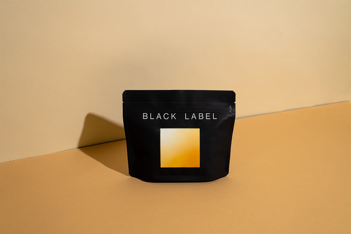A black 100g bag of coffee with a white, yellow and orange label gradient that describes the fruited notes and white floral aroma of this beautiful coffee. This coffee is from Gesha Village in Gesha Village, Ethiopia. 