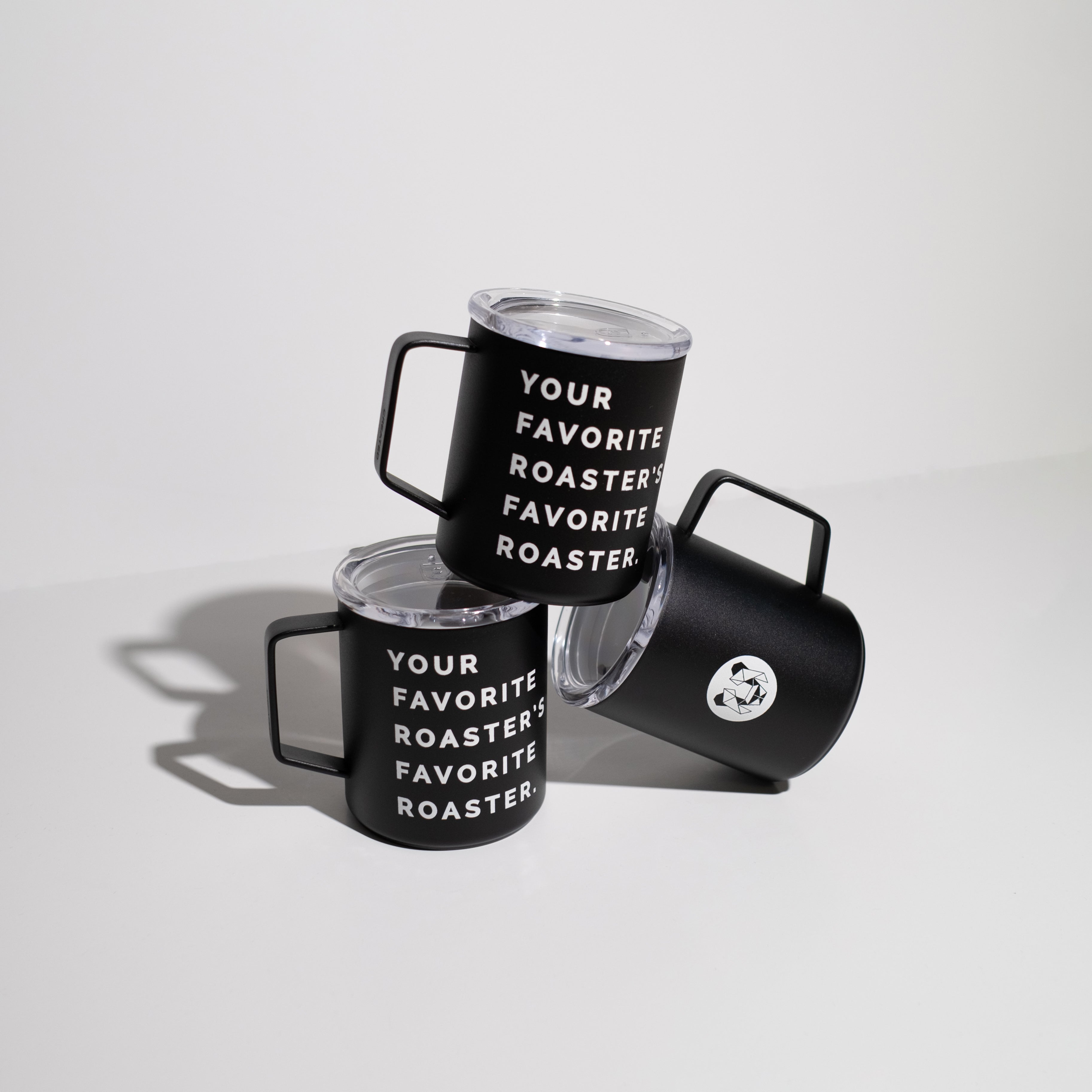 Multiple black enamel 12 ounce camp cups on a white background stacked for display. Cups have the statement, your favorite roaster, favorite roaster in white text on one side and a geometric panda on the other side.