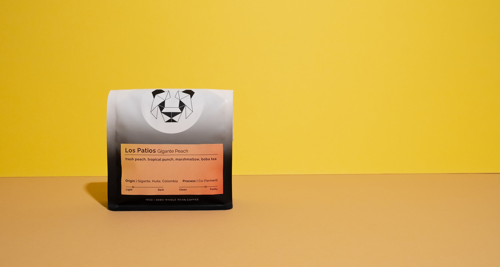 A bag of Los Patios coffee on a yellow and brown gradient background. The bag of coffee has tasting notes of fresh peach, tropical punch, marshmallow and boba tea. 