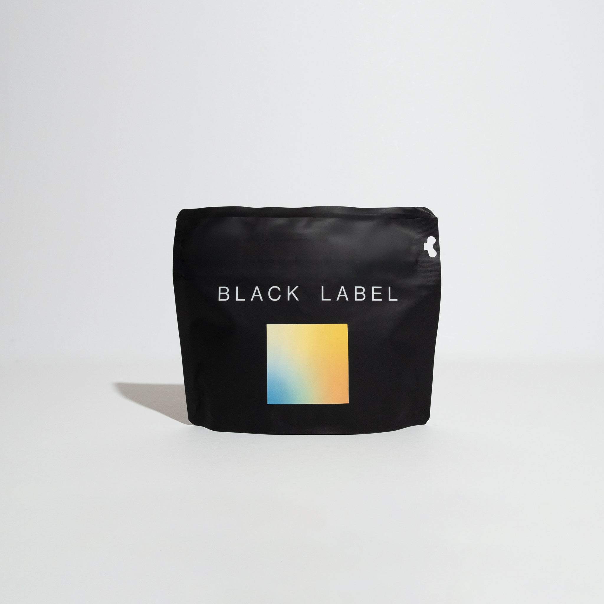 Matte-black pouch labeled BLACK LABEL, featuring a yellow-to-blue square graphic. Contains Iris Estate - Vivid Gesha, a specialty coffee from Panama's Iris Estate.