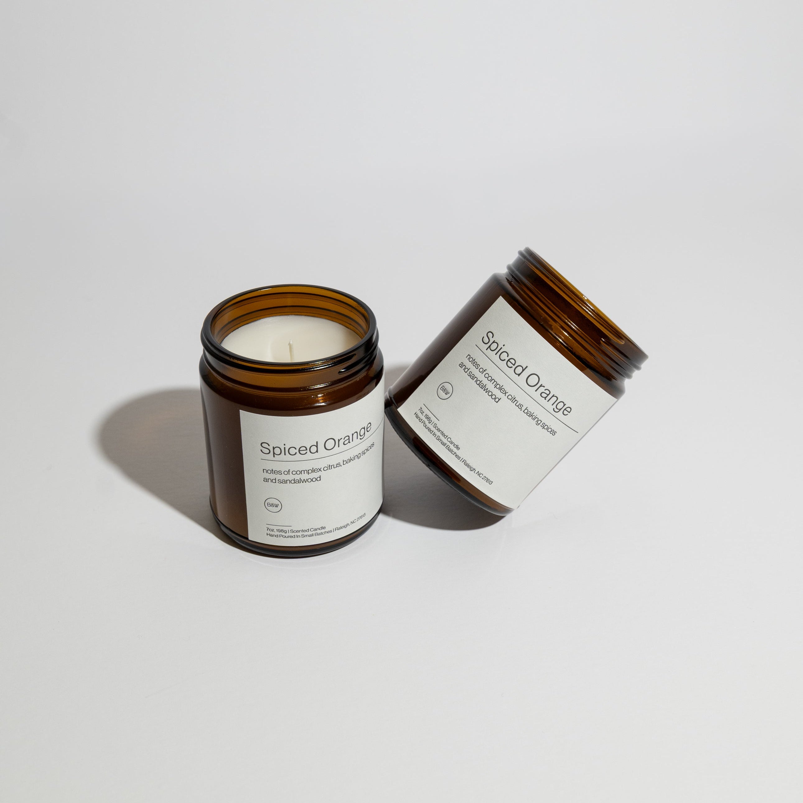 Spiced Orange candle in an amber jar with a white label on a light gray background